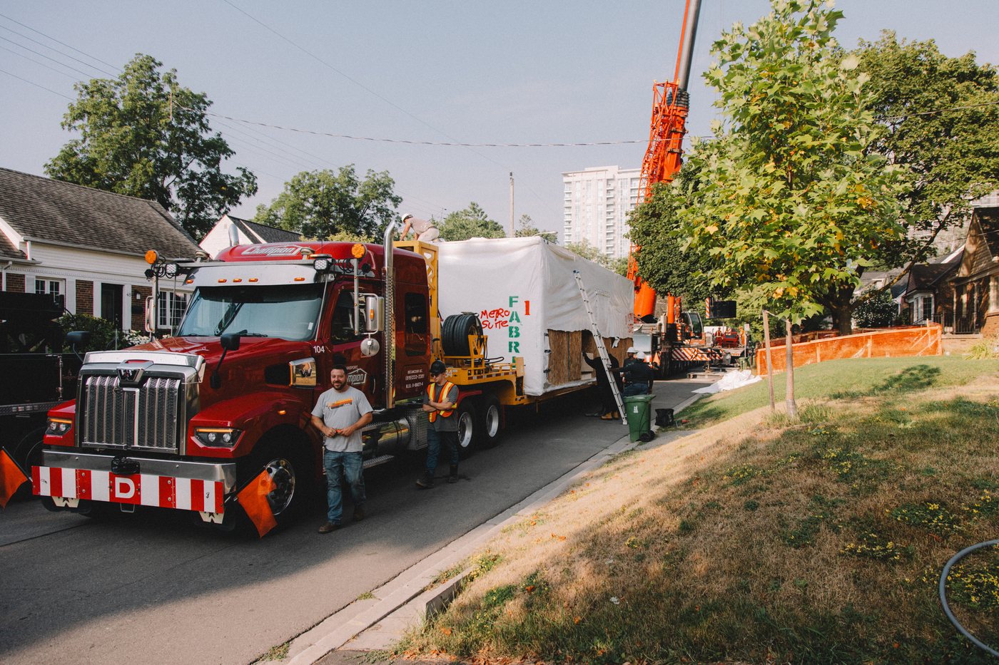 A crane truck and factory-built modules arriving on a North York street